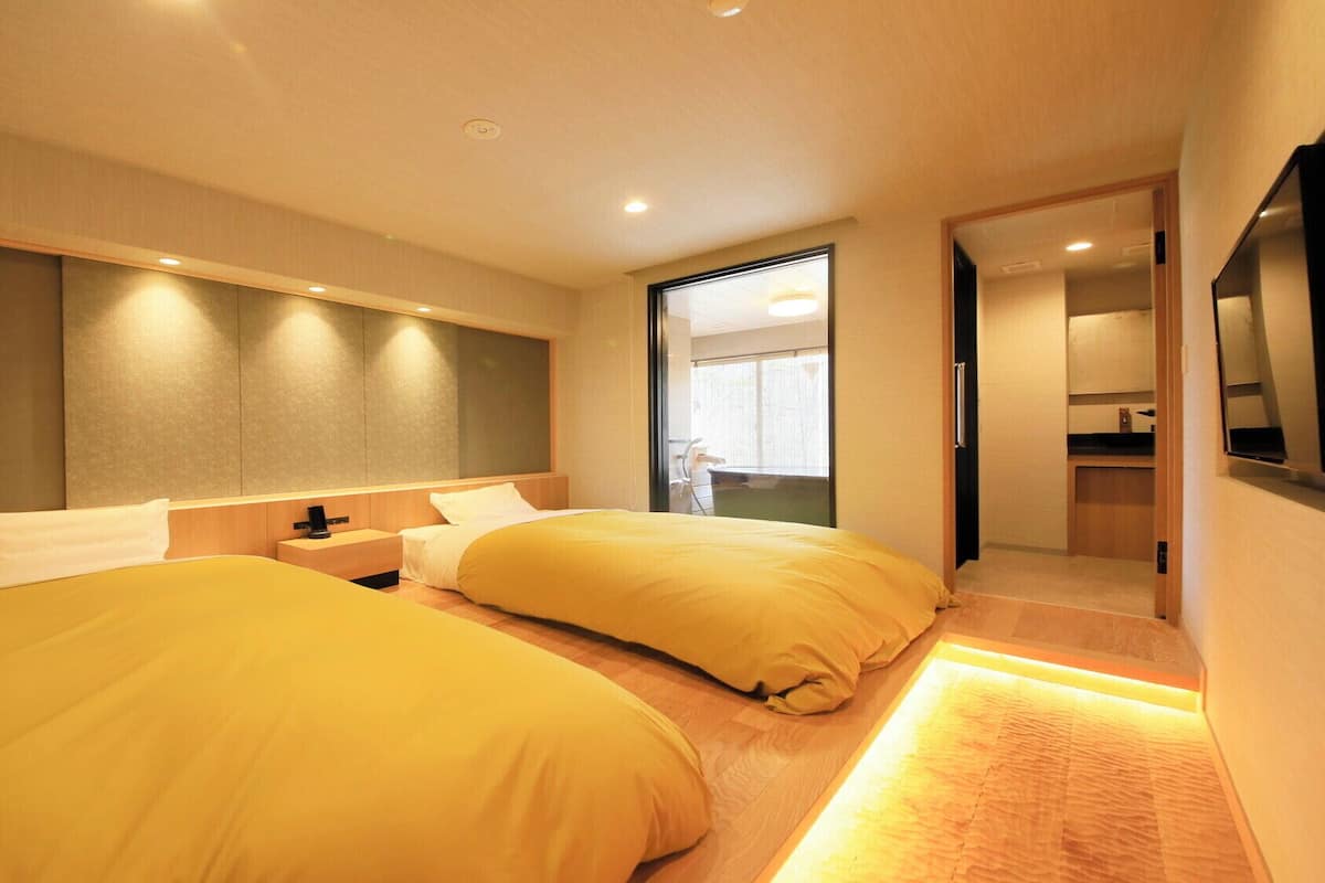 Une chambre d’hôtel moderne avec deux lits, un grand miroir et une vue sur un balcon.