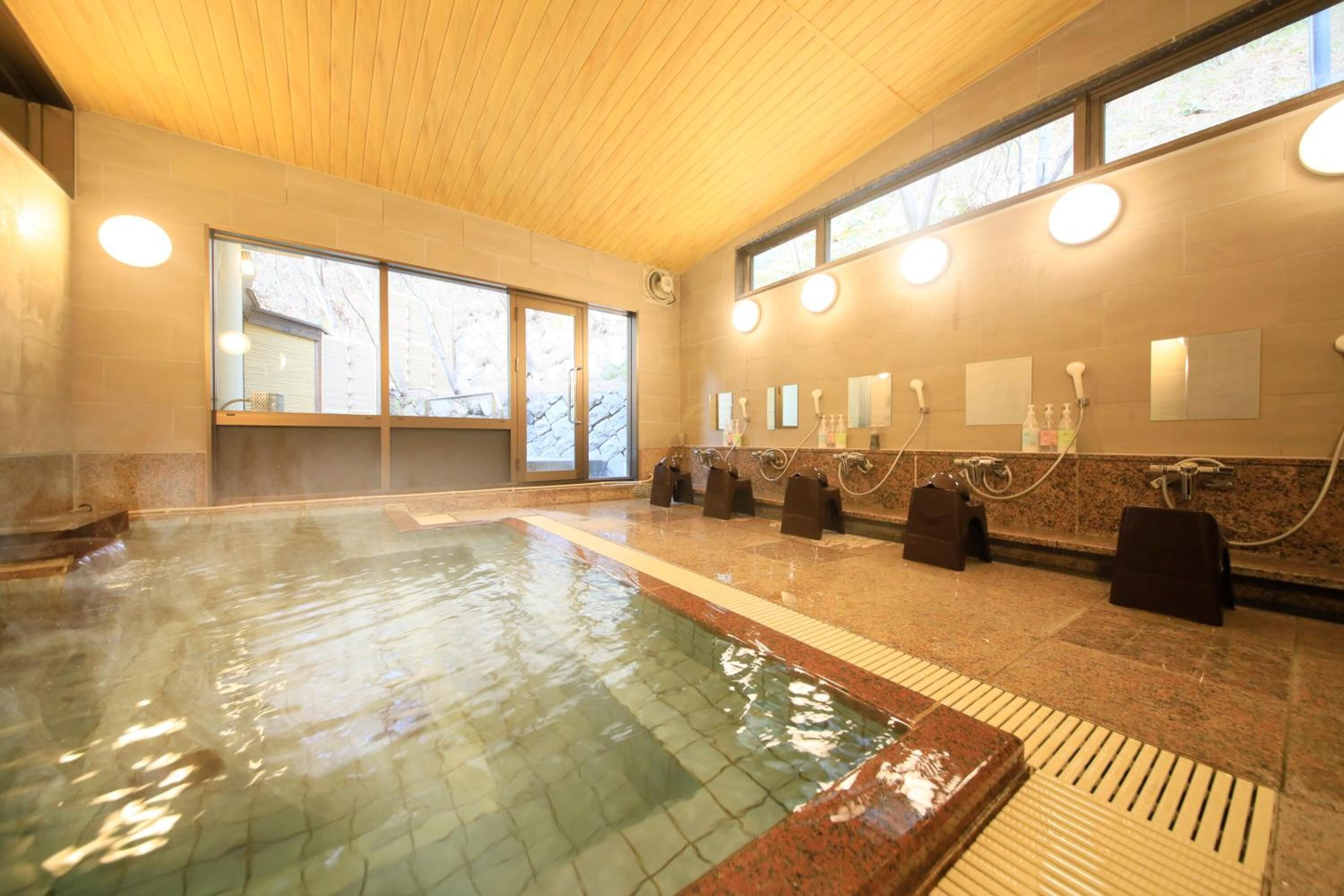A hot tub area with a wooden ceiling, large windows, and multiple towel dispensers.