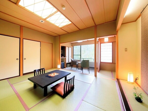 A tatami mat room with a low table and chairs, sliding doors, and a view of the outdoors. - Naruko Fuga (Osaki)