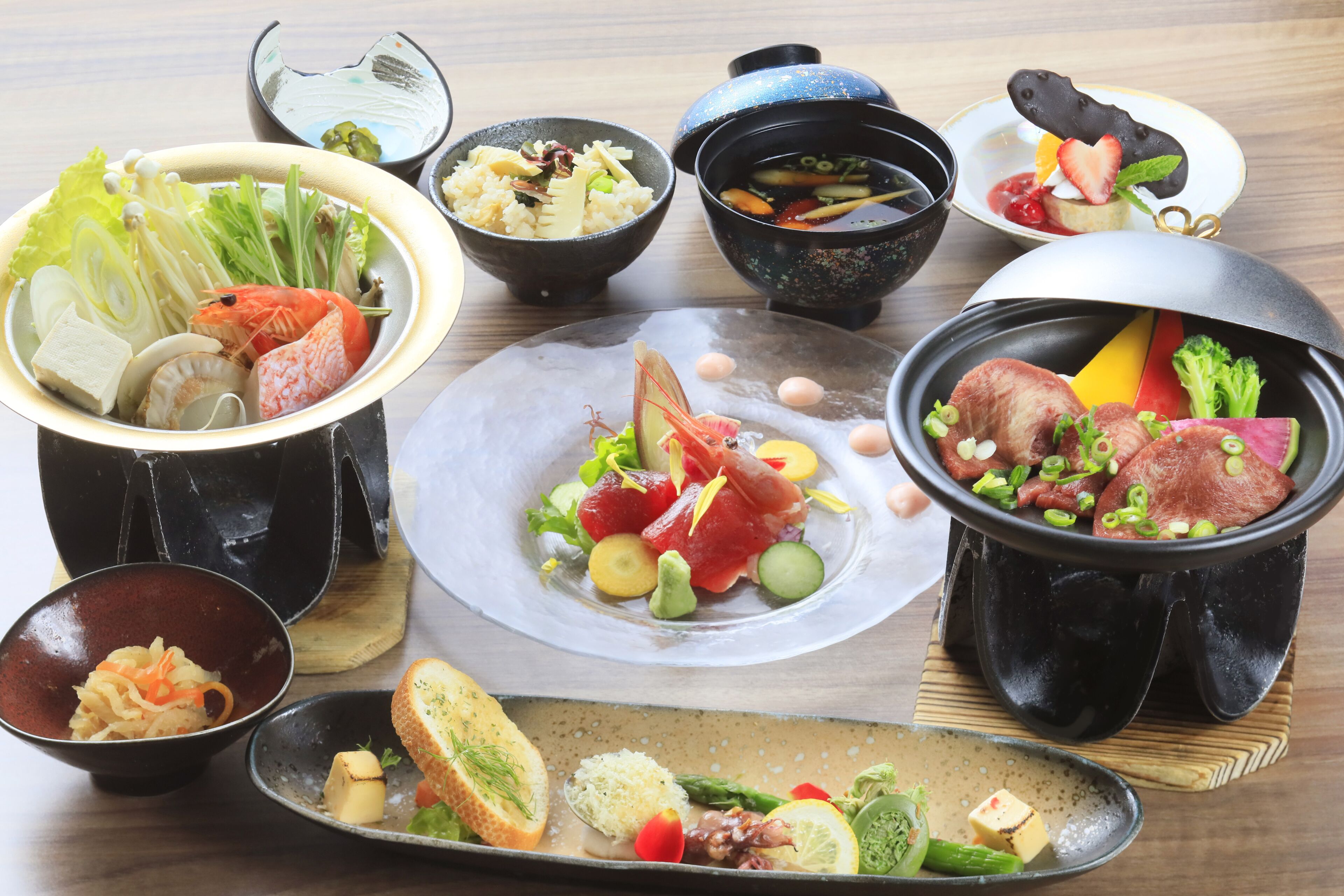 Diversos platos que incluyen mariscos, verduras y arroz, servidos en cuencos y platos negros tradicionales.