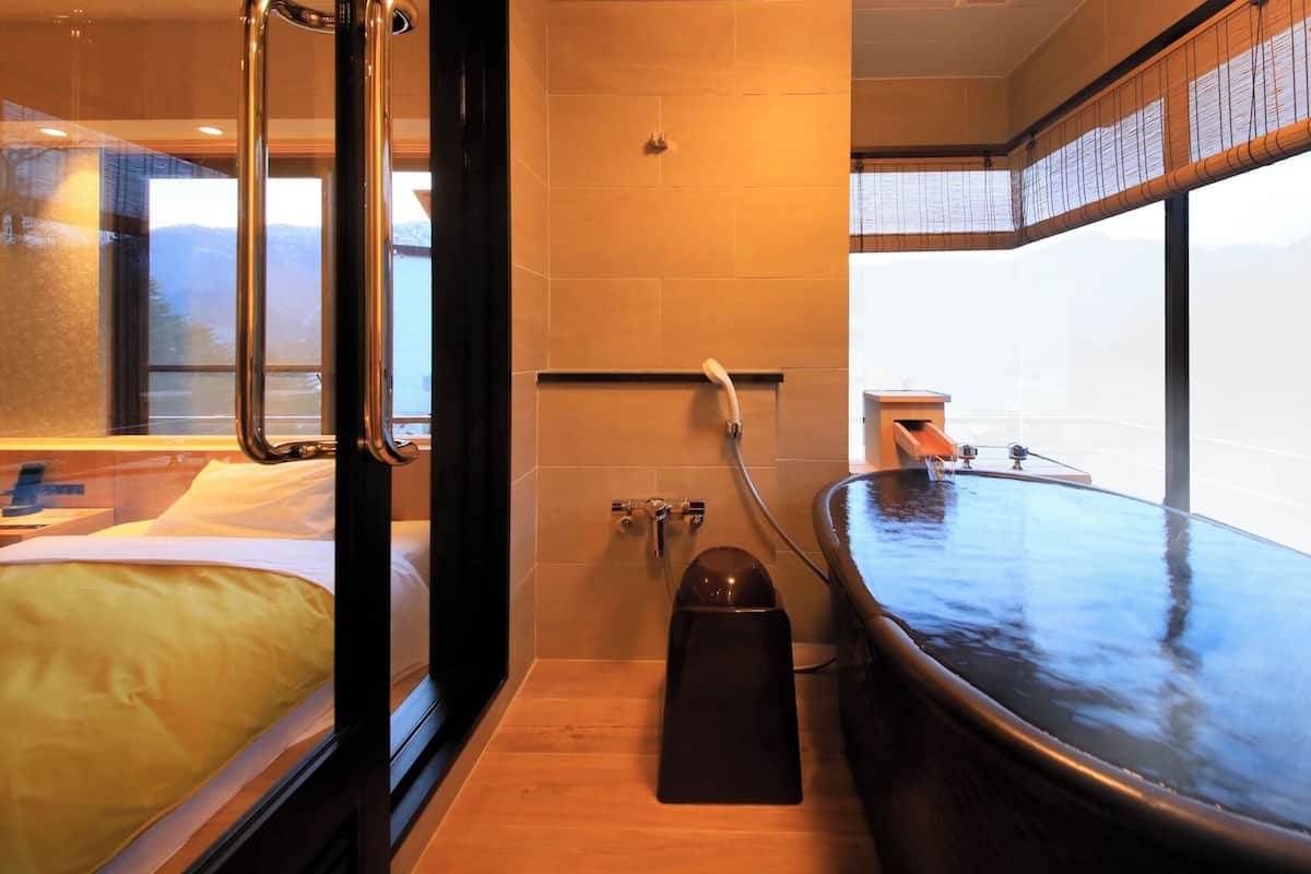 A modern bathroom with a bathtub, a shower, and a toilet.
