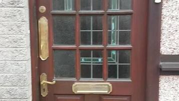 Una puerta de madera marrón con un panel de vidrio y un tirador de latón.