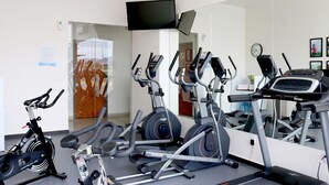 A gym with multiple exercise machines, a large mirror, and a television on the wall. - Hotel Misión Express San Juan Del Río (San Juan del Río)