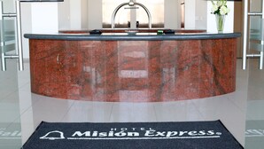 A reception area with a marble counter, two monitors displaying the hotel name, a sink, and a welcome mat. - Hotel Misión Express San Juan Del Río (San Juan del Río)