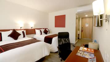 Habitación de hotel con dos camas, un escritorio, una silla y una lámpara.