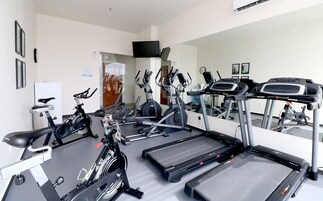 A gym with various exercise equipment including treadmills, stationary bikes, and elliptical machines.