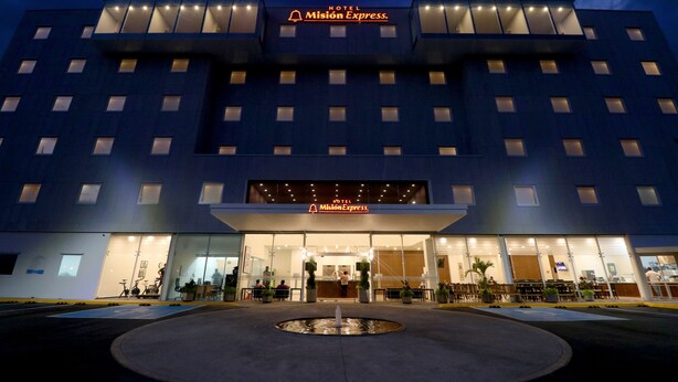 A modern hotel with a prominent sign, a central entrance, and a water feature in front. - Hotel Misión Express San Juan Del Río (San Juan del Río)
