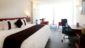 A hotel room with a large bed, a desk, a chair, and a bicycle. - Hotel Misión Express San Juan Del Río (San Juan del Río)