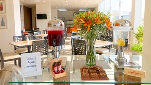 A hotel reception area with a glass counter displaying a water dispenser, a vase with orange flowers, and a sign indicating 'Aguaje jamaica'. - Hotel Misión Express San Juan Del Río (San Juan del Río)