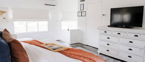 A bedroom with a bed, a TV, a dresser, and a ceiling fan.