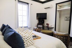 Et hotelværelse med en seng, et fjernsyn, et lille bord og en stol.