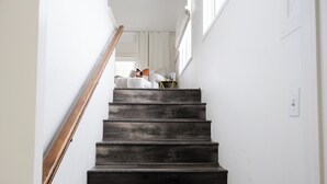 A staircase with dark wooden steps leading to a landing area with a white wall and a window. - The Evers House (Fredericksburg)