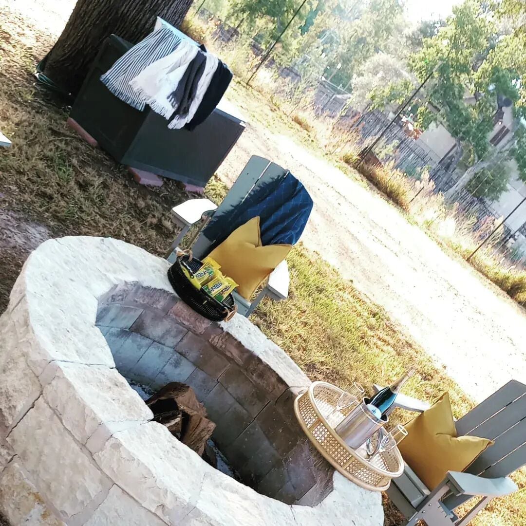Un hogar de piedra con parrilla de metal, rodeado por un muro de piedra.