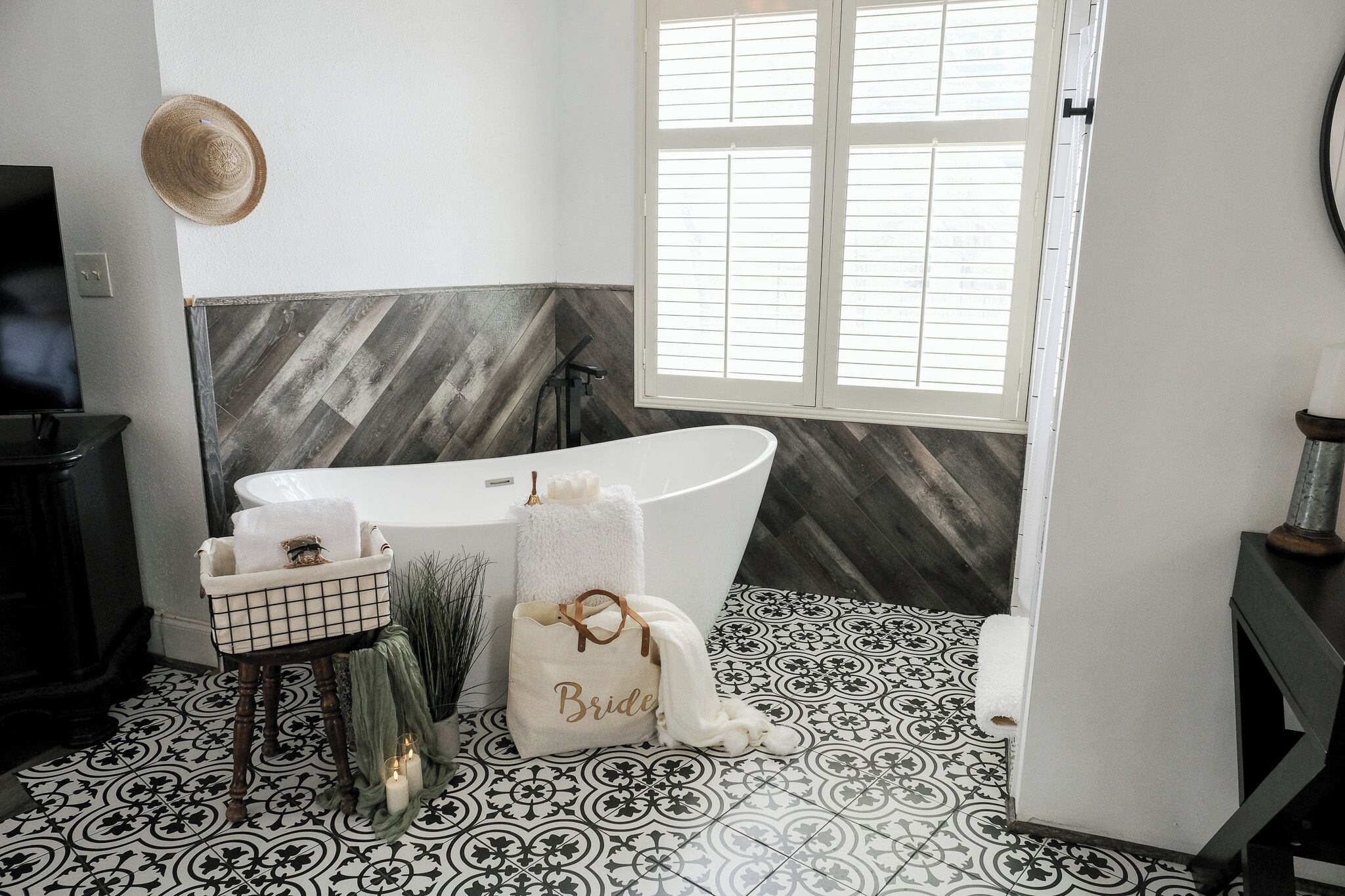 Une salle de bain avec une baignoire sur pieds, un meuble-lavabo avec un miroir, un porte-serviettes et un chapeau décoratif accroché au mur.