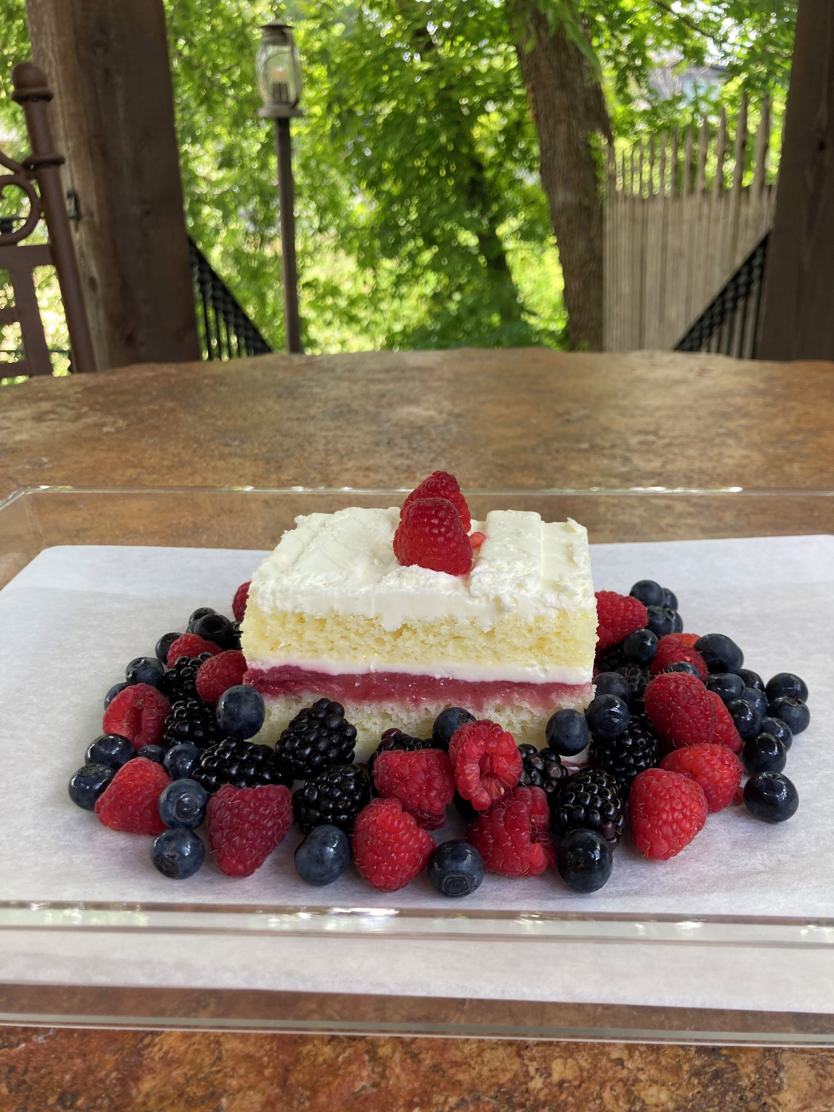 Un dessert servi dans une assiette blanche, composé d’une part de gâteau, de crème et de fruits rouges.