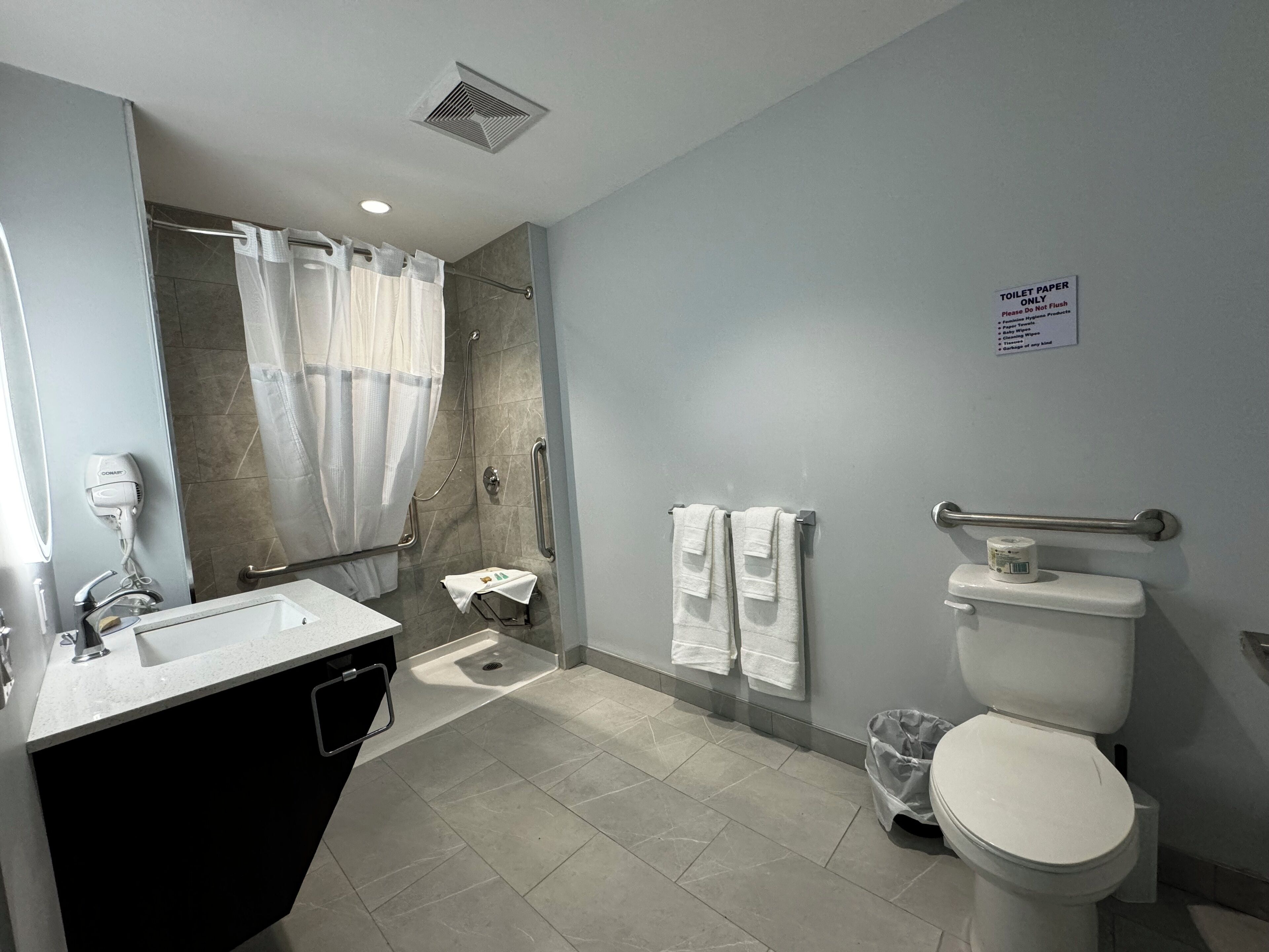 Een moderne badkamer met douche, toilet en wastafel.