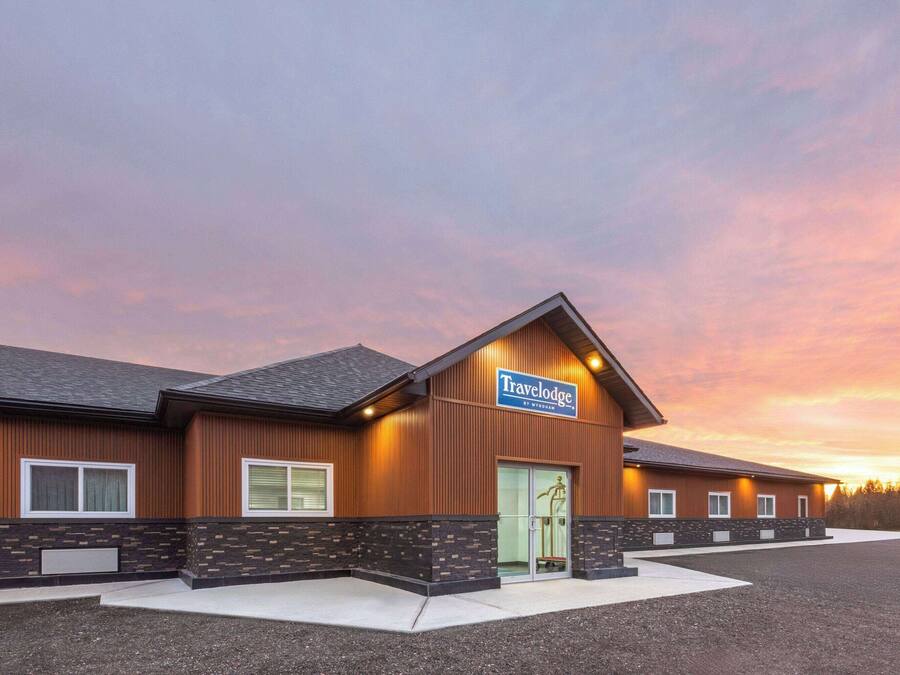 Un hotel Travelodge con diseño moderno, que cuenta con un letrero destacado, un amplio estacionamiento y una entrada bien iluminada.
