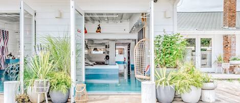 A modern building with a pool, potted plants, and a covered entrance.