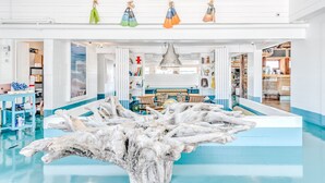 A spacious lobby with a central water feature, a seating area, and a view into the kitchen. - The Surf Lodge (Montauk)