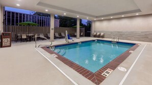 Une piscine bordée de briques, un espace détente avec des tables et des chaises, et une terrasse couverte avec des parasols.