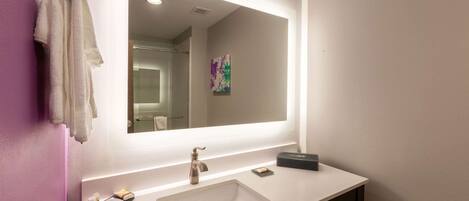 A modern bathroom with a white sink, a large mirror, and a towel rack.