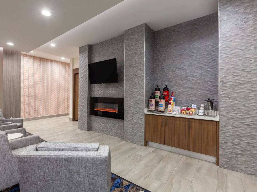 A modern living area with grey sofas, a fireplace, a flat-screen TV, and a minibar.