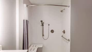 A shower with a handheld showerhead, a wall-mounted faucet, and a grab bar.