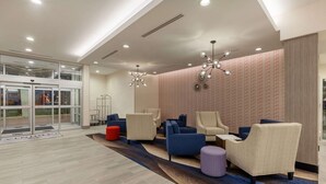 Un hall d’entrée avec des sièges, un mur décoré de motifs et une entrée en verre.