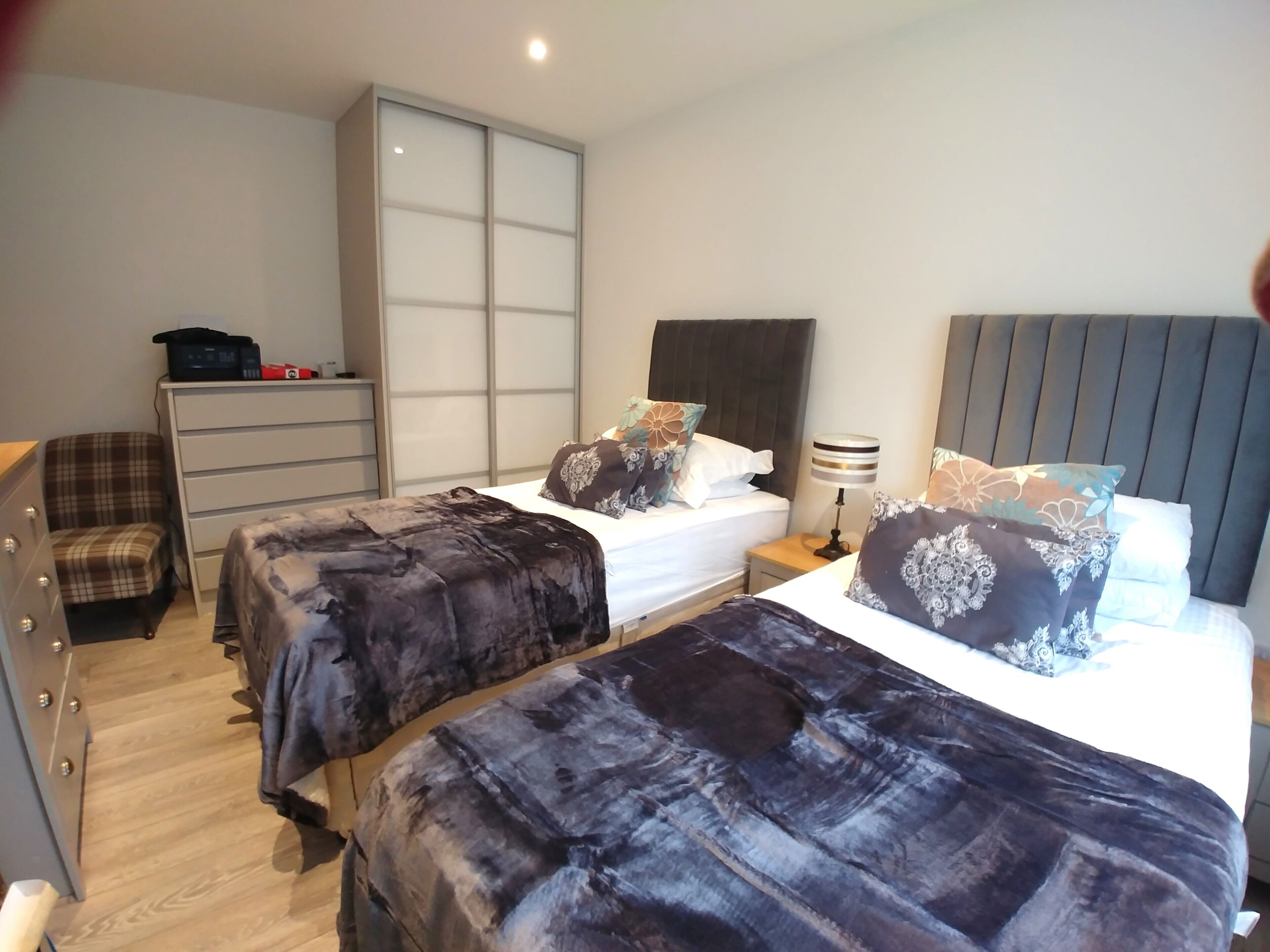 A hotel room with two beds, a wardrobe, a desk, and a chair.