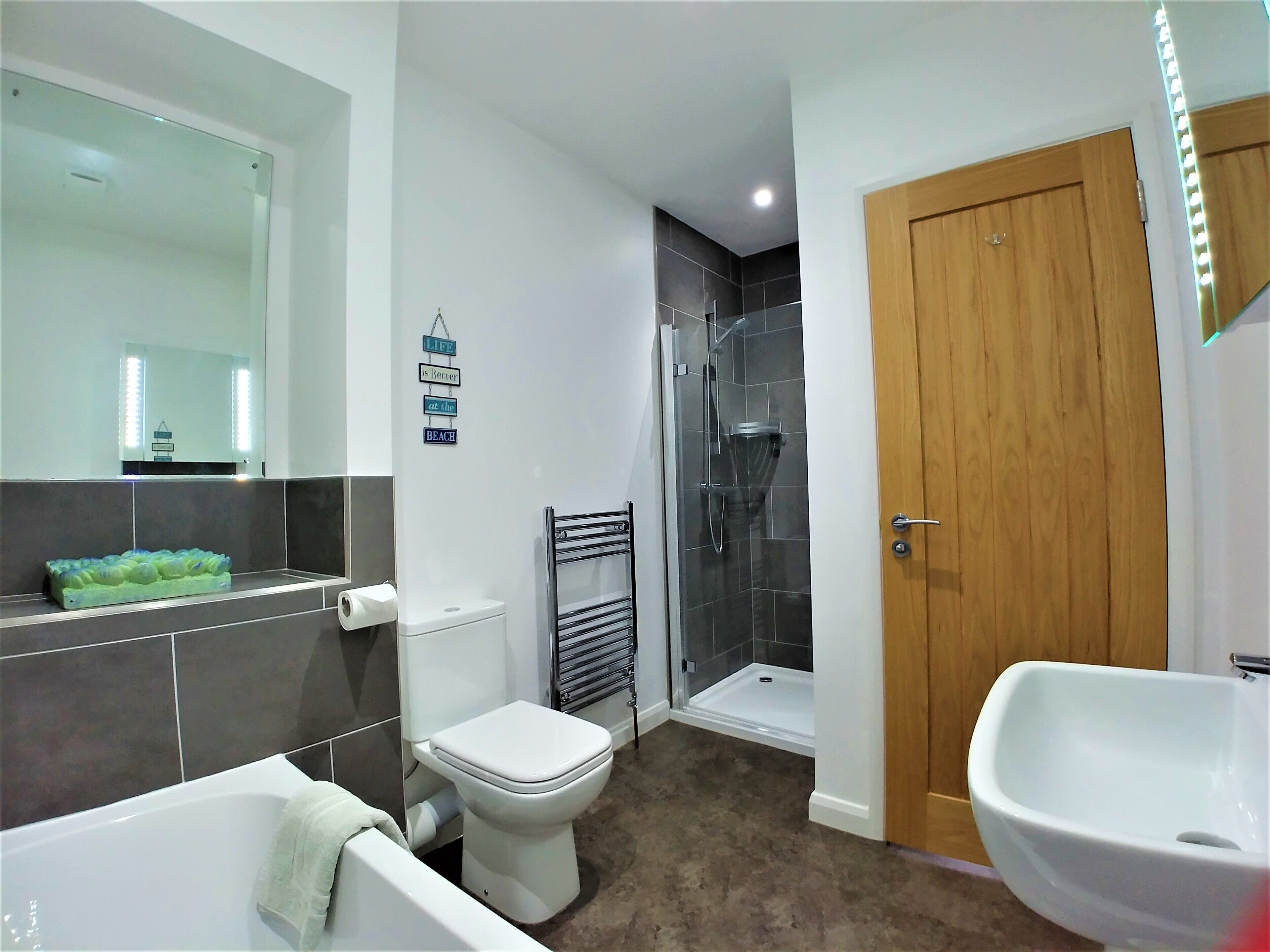 Une salle de bain moderne équipée d’une baignoire, de toilettes, d’une douche et d’un lavabo.
