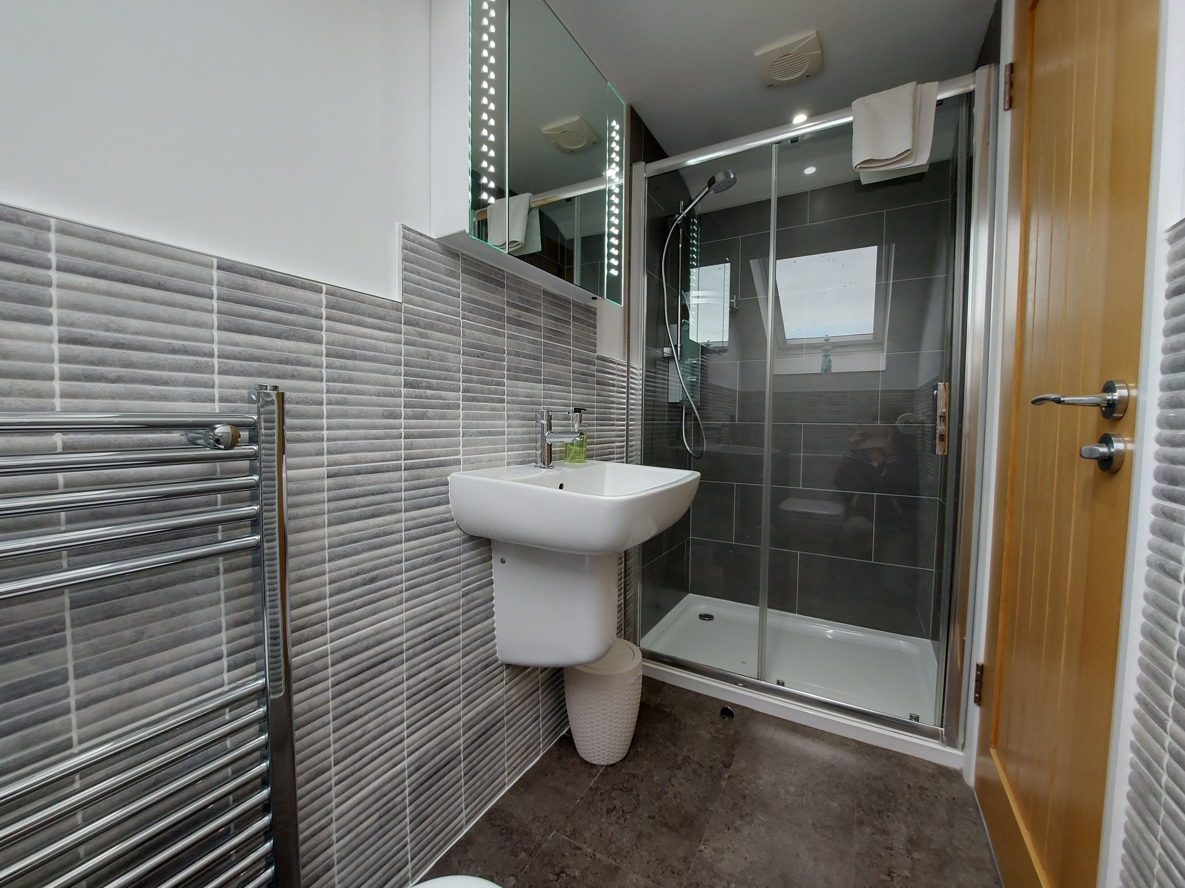 Une salle de bain moderne avec une douche à parois de verre, un lavabo blanc et un porte-serviettes.
