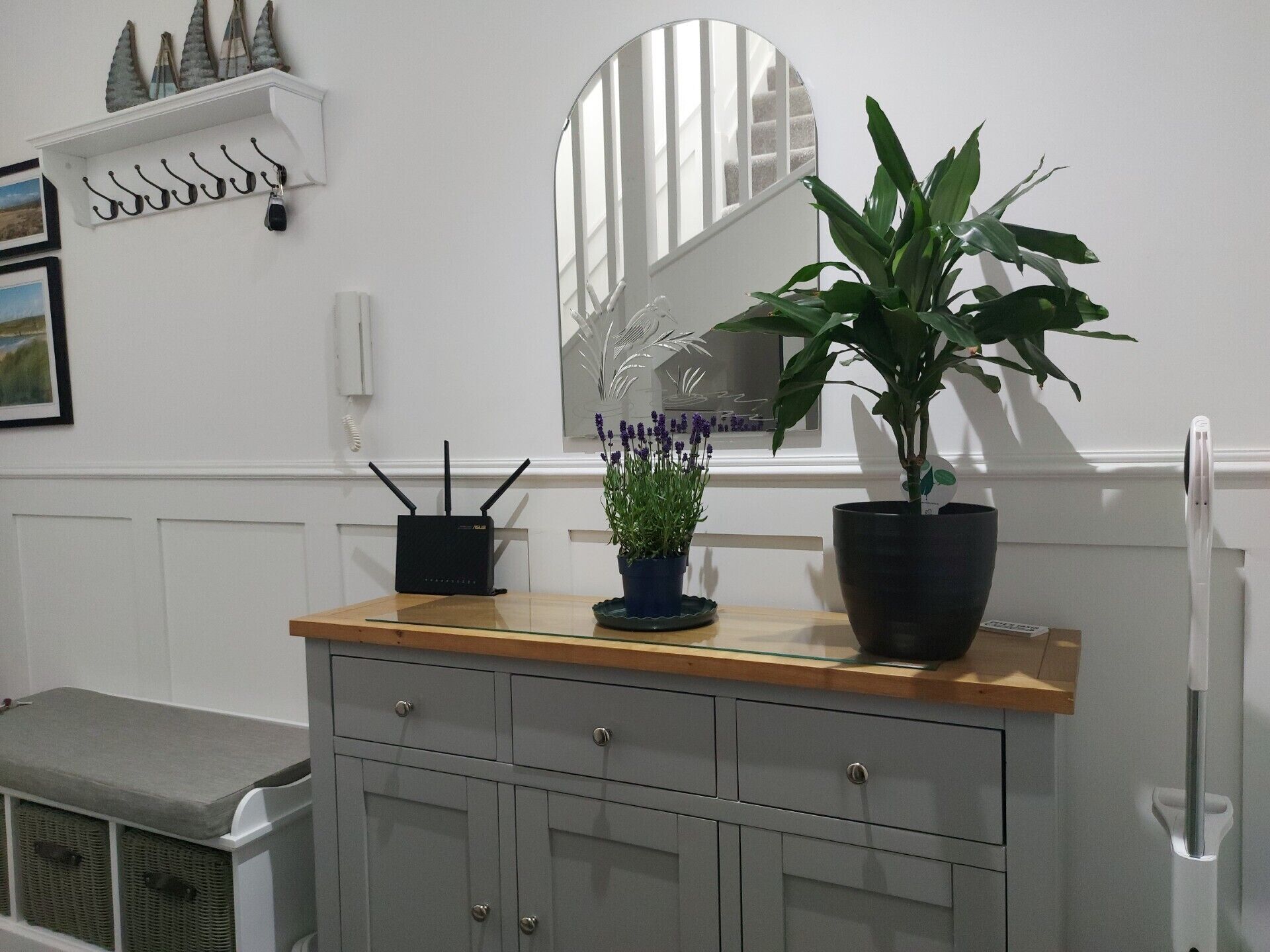 Una habitación con mostrador de madera, una planta en maceta, un espejo, perchero y radiador.