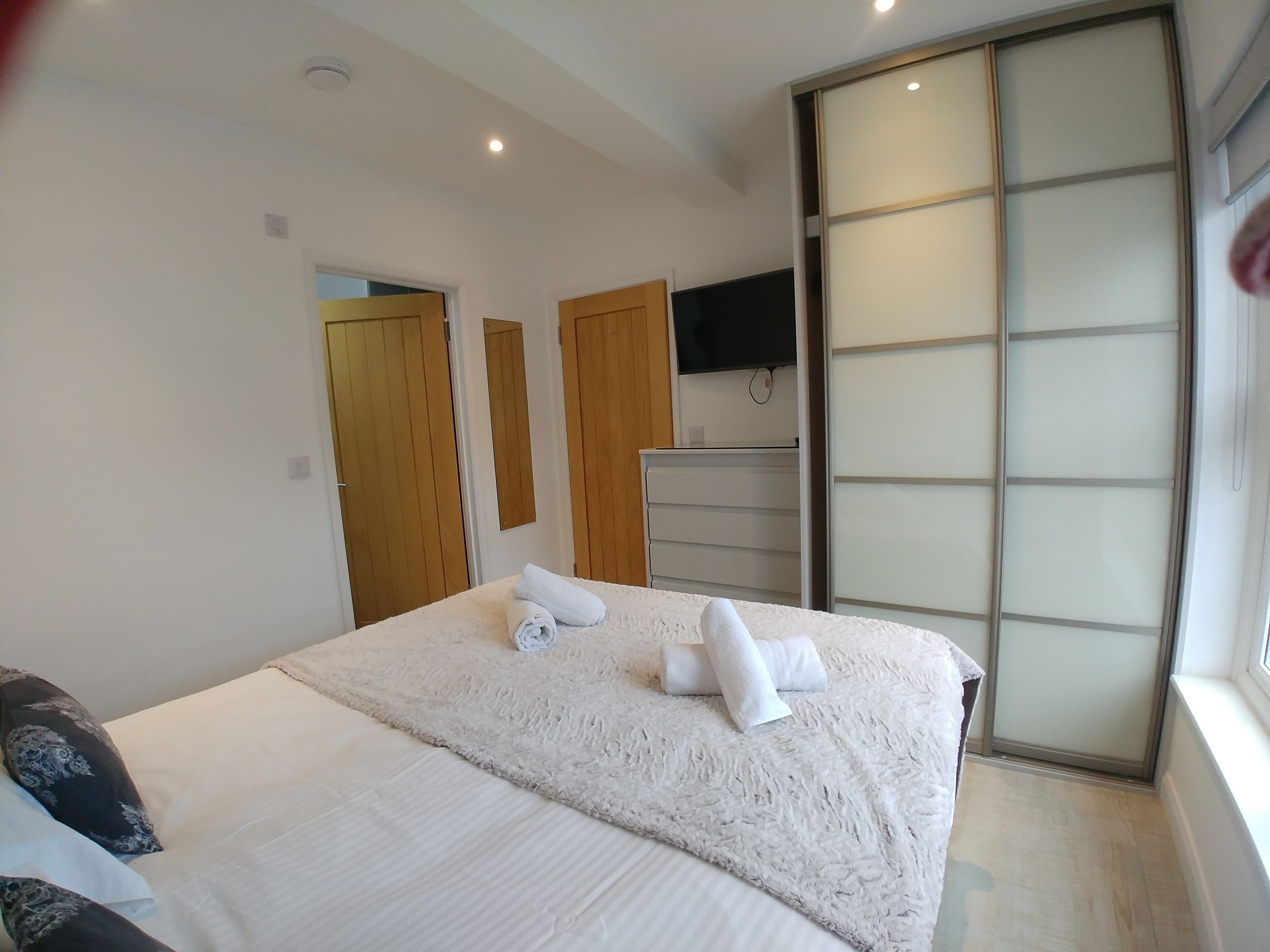 Een moderne hotelkamer met een groot bed, een flatscreen televisie aan de wand en een schuifdeurkast.