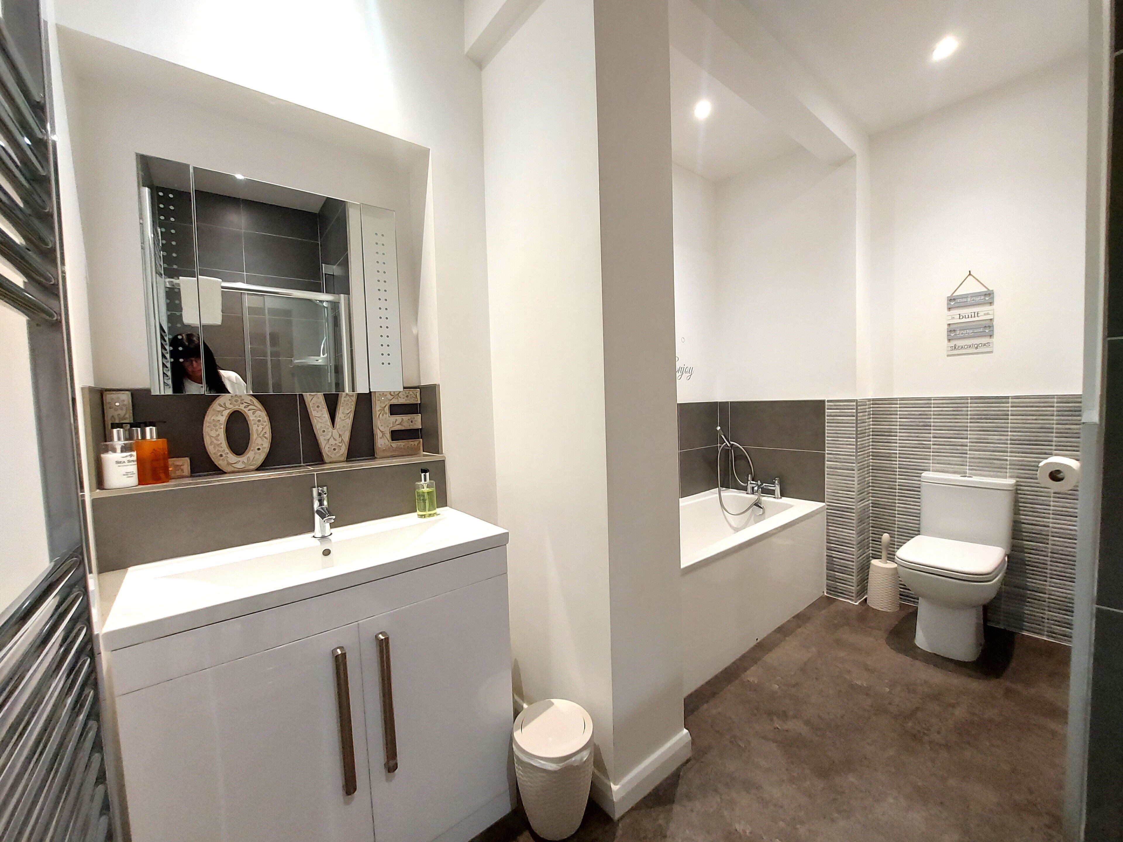 A modern bathroom with a vanity, toilet, and bathtub.