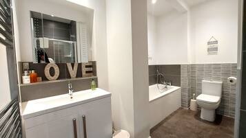 A modern bathroom with a vanity, toilet, and bathtub.