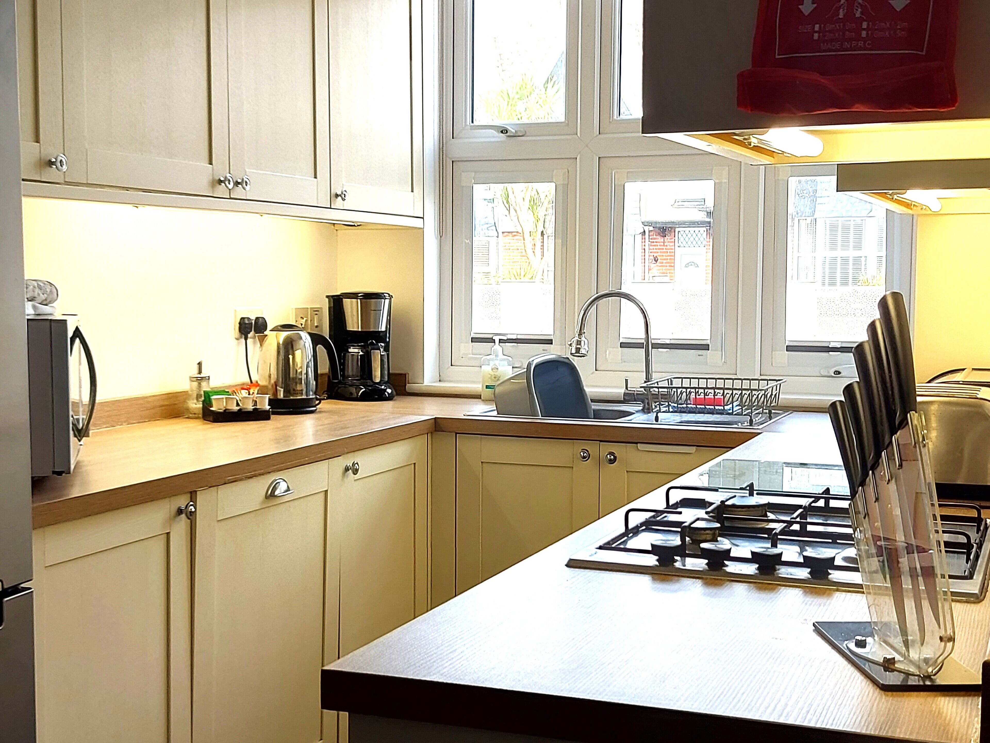 A kitchen with a gas stove, a coffee maker, and a sink.