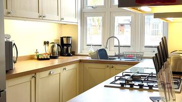 A kitchen with a gas stove, a coffee maker, and a sink.