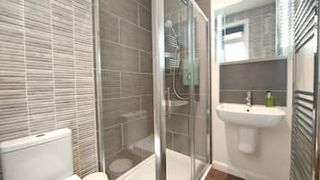A modern bathroom with a glass shower enclosure, a white sink, and a toilet.