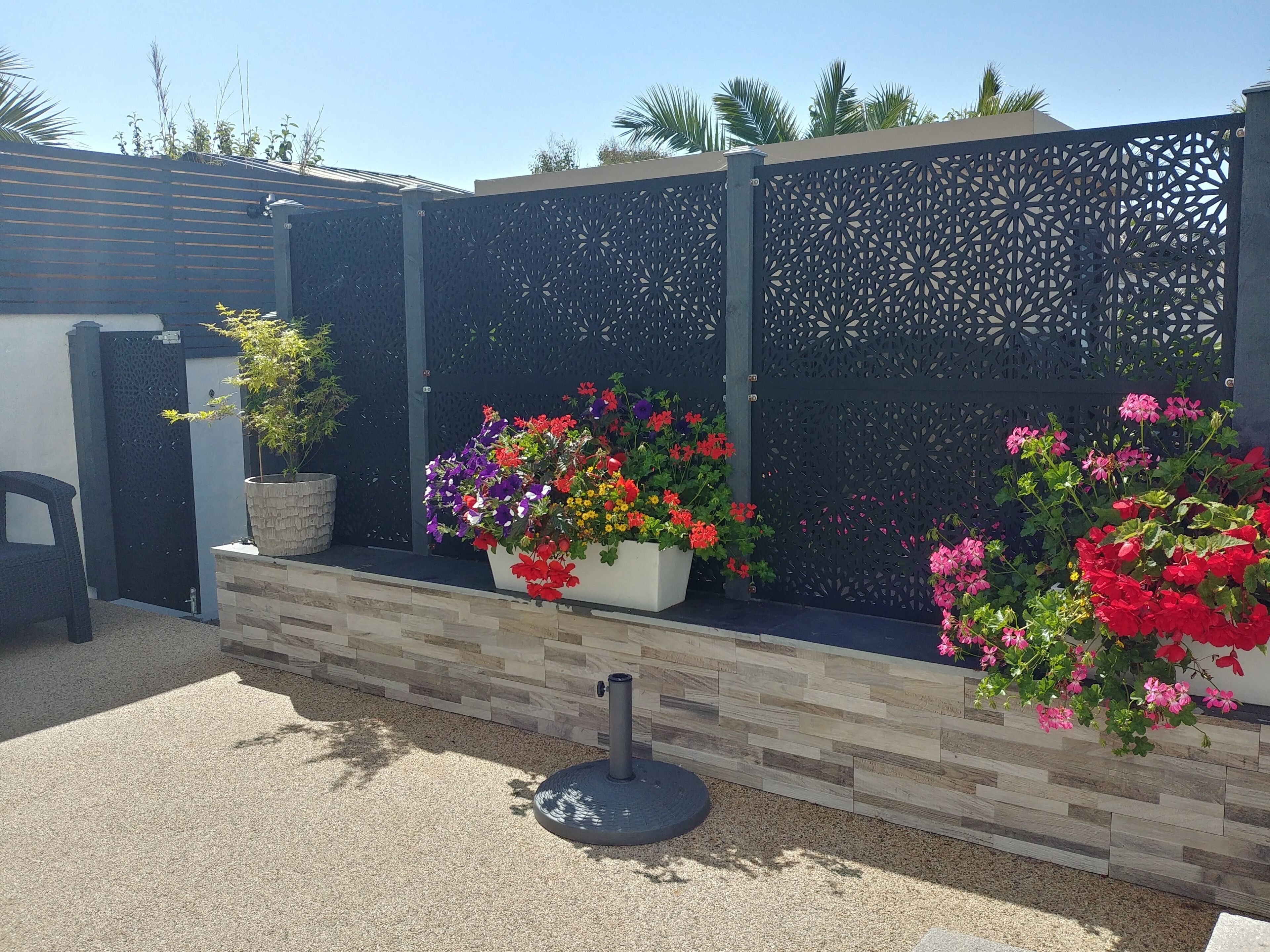 A garden area with a decorative fence, potted plants, and a seating area.