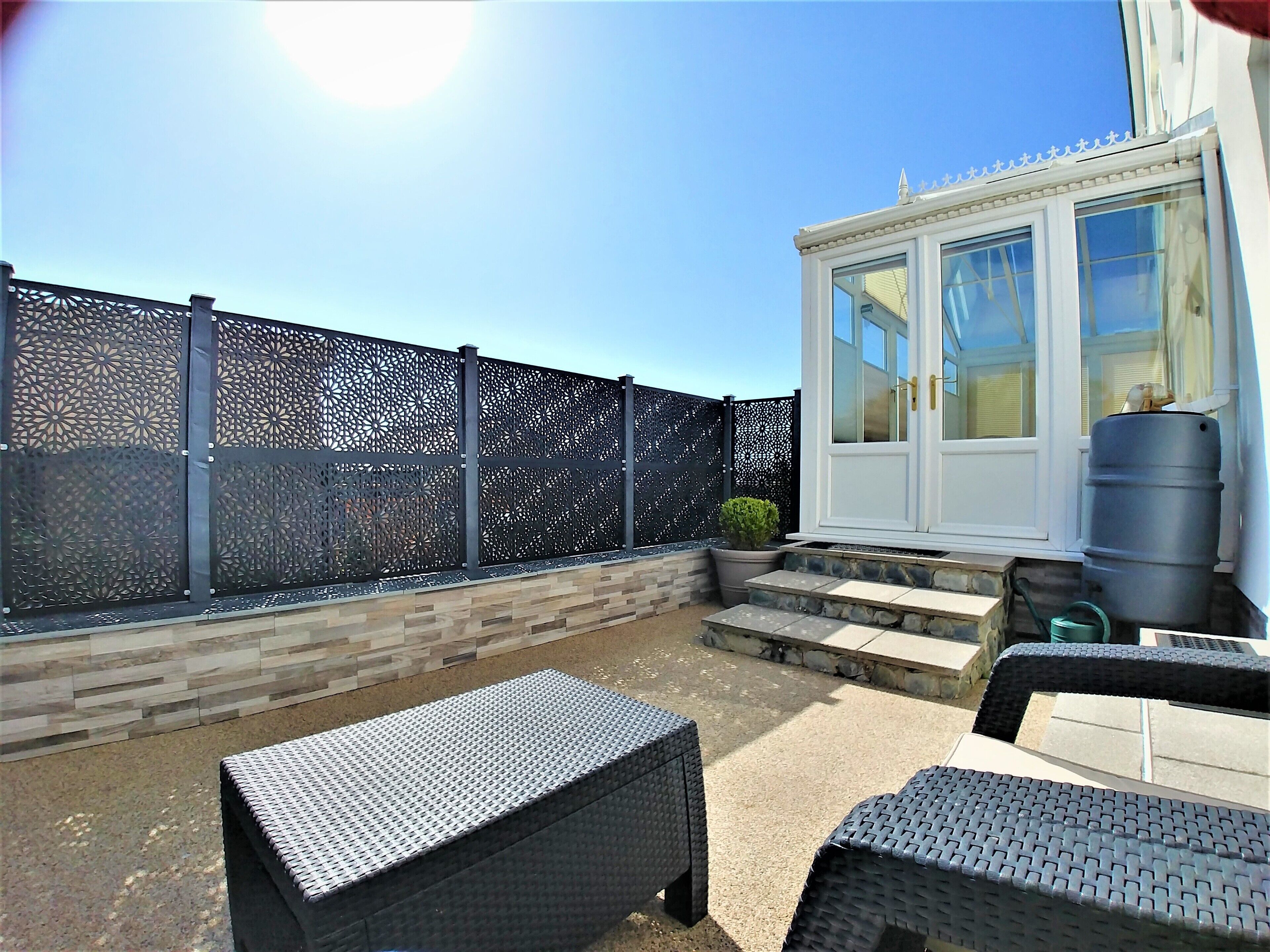 A patio area with a decorative fence, a white door, and a water tank.