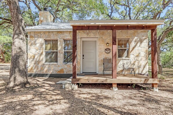 A stone house with a wooden porch and a door.
