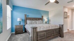 A bedroom with a wooden bed, two bedside tables with lamps, a ceiling fan, and a window with blinds. - Elegant & beautiful 6 bedroom pool home with game room, in popular ChampionsGate (Davenport)