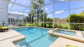 A swimming pool with a glass enclosure, a lounge chair, and a hot tub. - Elegant & beautiful 6 bedroom pool home with game room, in popular ChampionsGate (Davenport)
