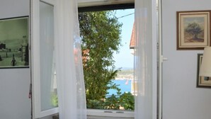 Ett rum med ett fönster, en inramad tavla på väggen och en lampa.