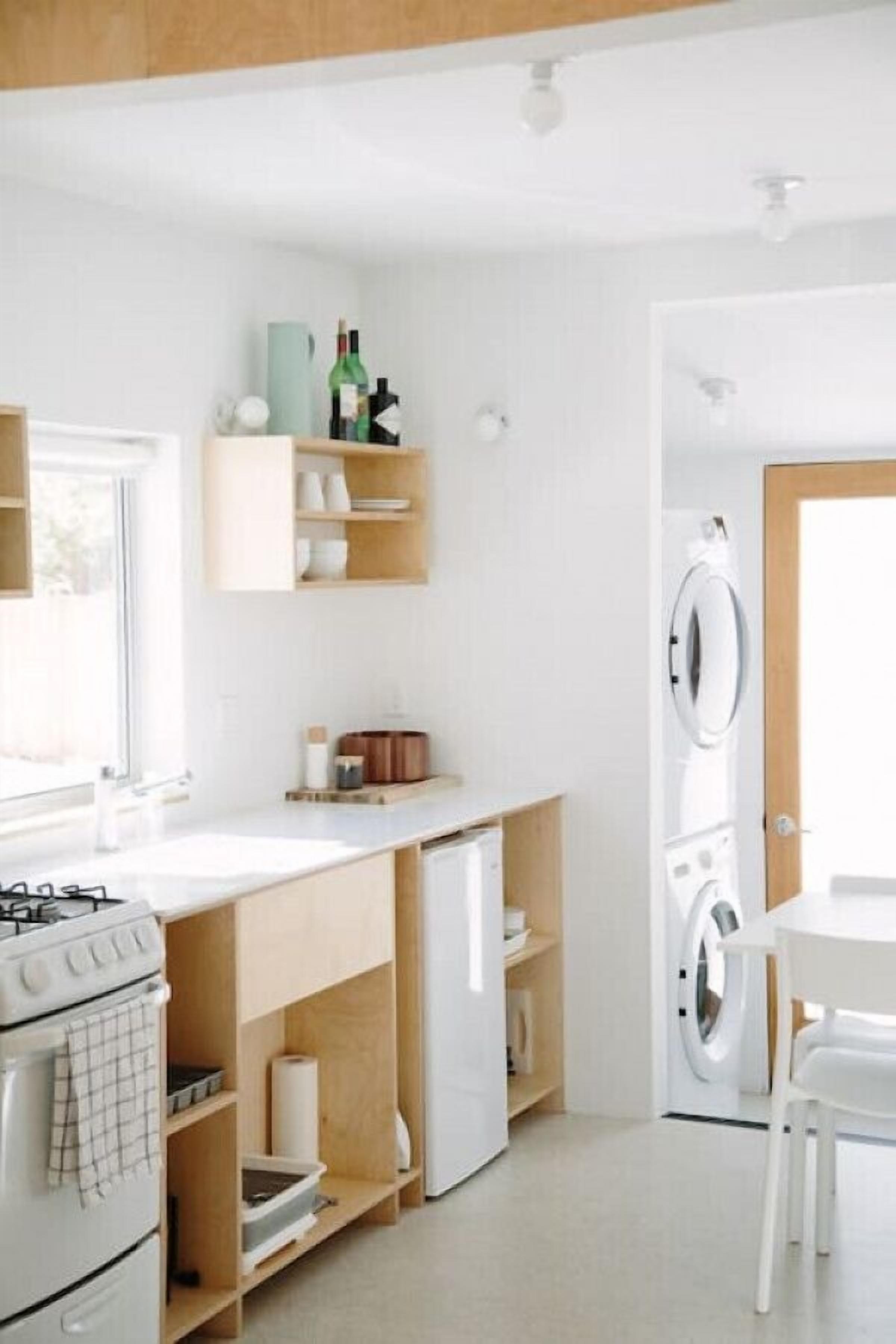 A compact kitchen with a stove, oven, and built-in shelves.