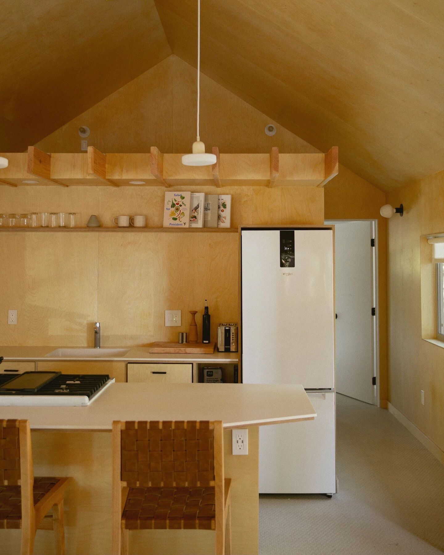 A modern kitchen with wooden cabinetry, a built-in island, and a white refrigerator.