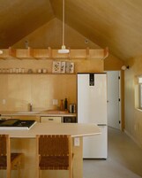 A modern kitchen with wooden cabinetry, a built-in island, and a white refrigerator.