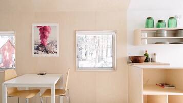 A modern kitchen with a white table and chairs, a window with a snowy view, and a shelf with jars.