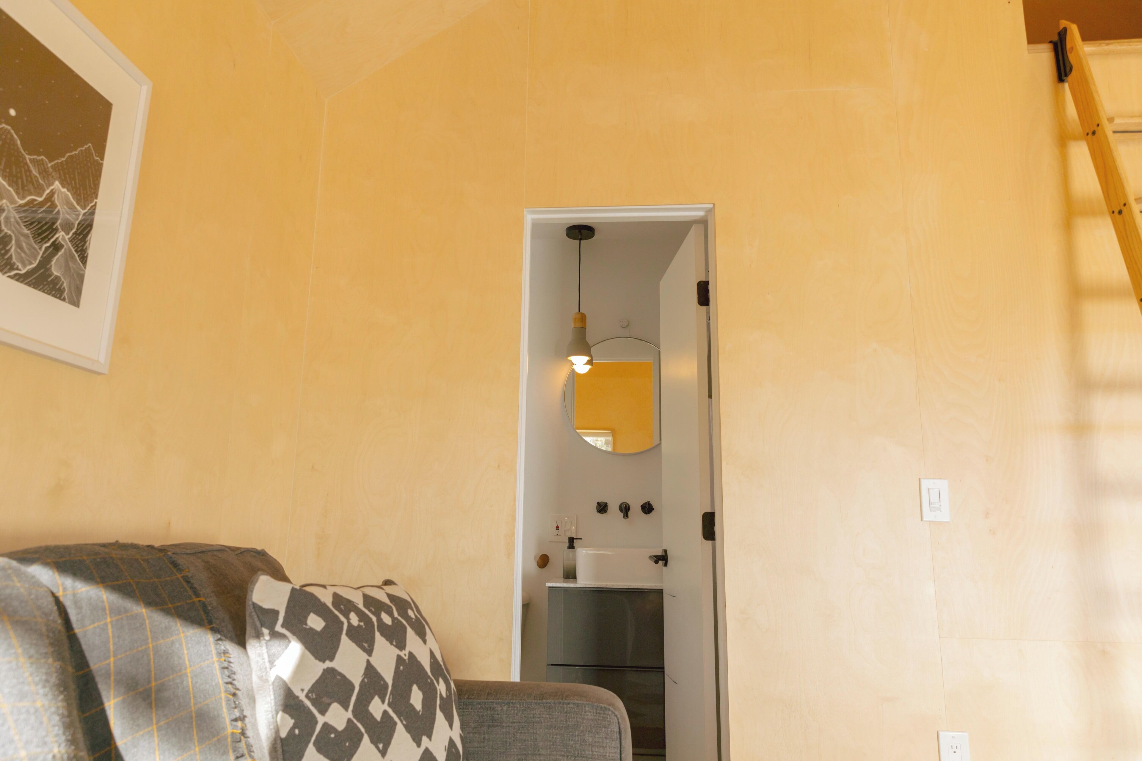 A room with a sofa, a door leading to a kitchen, and a wall-mounted mirror.