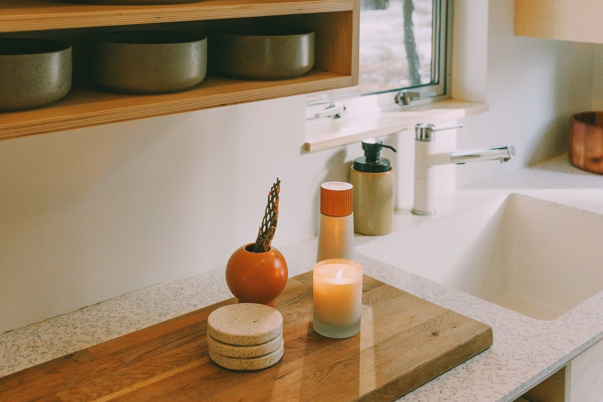A kitchen with wooden shelves, a window, and a countertop with a candle and decorative items.